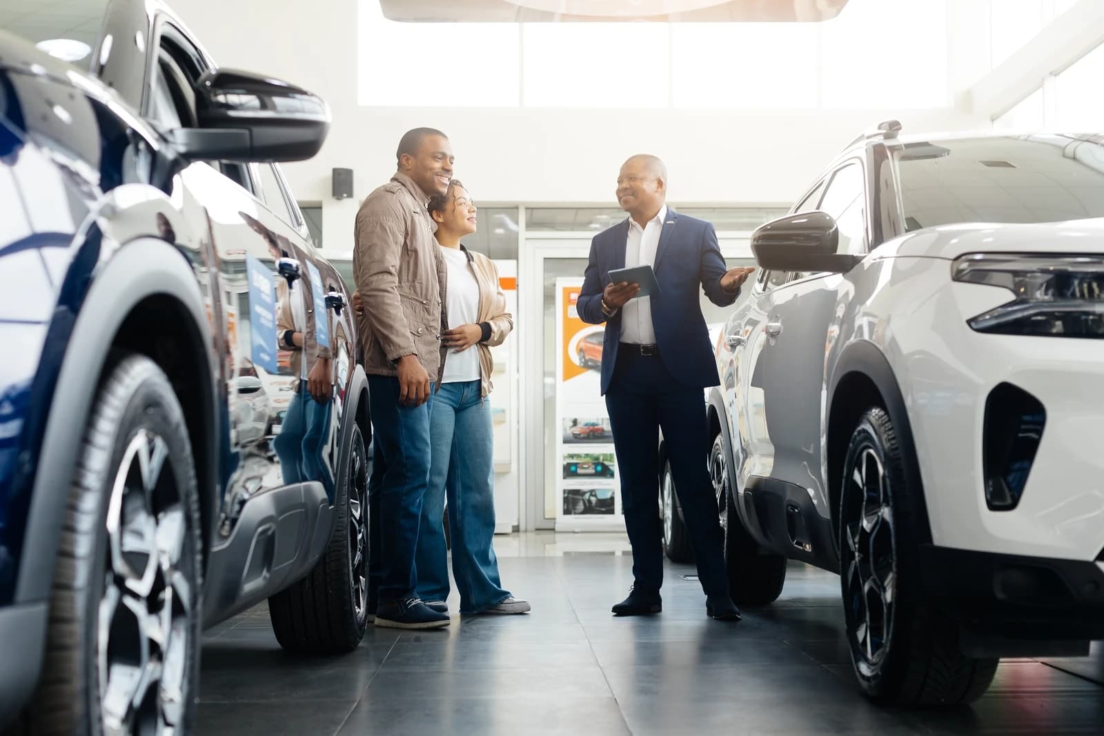 Dealership salesperson showing a car to a couple in a showroom