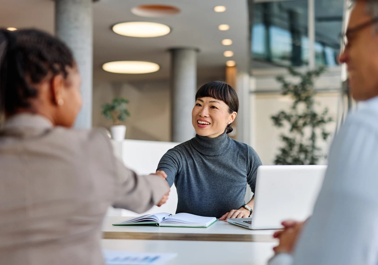 Debt advisor shaking hands with a client across a desk